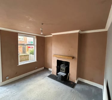 Empty living room with fresh brown plaster walls, a wood-burning stove, and grey carpet.