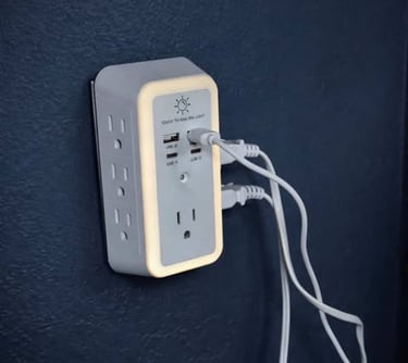 Wall-mounted outlet extender with built-in night light and USB ports charging multiple devices