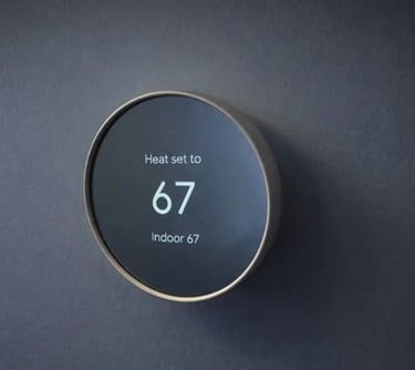 Wall-mounted smart thermostat displaying heat set to 67 degrees with indoor temperature shown
