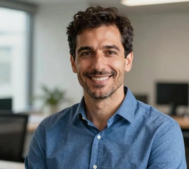 A professional headshot of a friendly man in his 40s in a Southern European / Italian office environment, wearing a professional steel blue shirt, soft natural lighting, high-quality portrait photography.