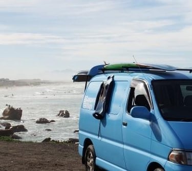 a van parked on the beach with surfboards on the beach