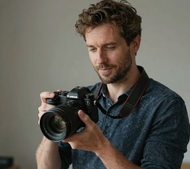 Portrait of a Southern European man holding a professional camera in a studio setting. Natural lighting, sophisticated and approachable vibe.