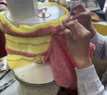 a person is sewinging a sweater with a yellow and red scarf