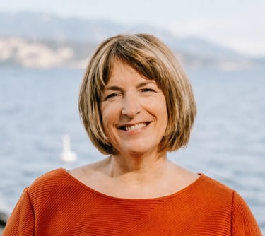 a senior short blonde hair lady, named Susan Noble, with okanagan lake on her back