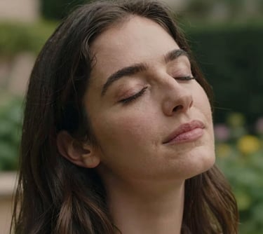 A close-up portrait of a woman with a gentle expression, eyes closed in a moment of peace, outdoor lighting in a Spanish garden, professional photography, empathetic atmosphere.