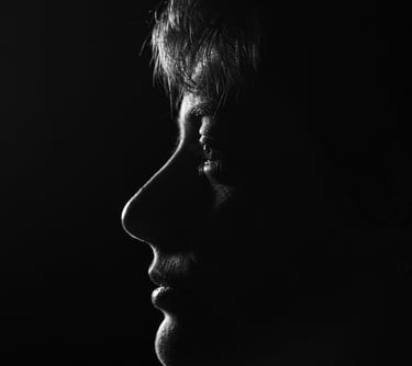 Dramatic black and white profile portrait of a woman using low-key lighting against a dark background.