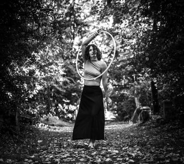 Photo artistique en noir et blanc d'une femme vêtue d'une jupe faisant du cerceau