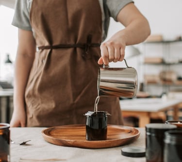 a person in a apron is pouring coffee into a cup