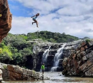 Lady jumping out of Baboon cave with Strandlooper falls behind her