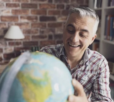 Homem sorridente segurando globo terrestre, representando expatriados e mobilidade global.