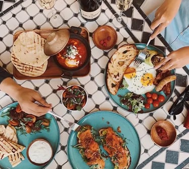 Brunch gourmand avec viennoiseries, fruits frais et fleurs, servi dans une location de charme