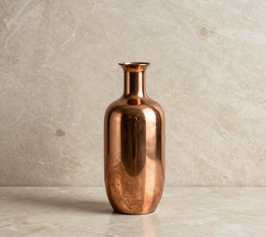 A minimalist interior design shot featuring a copper vase and refined decorative elements on a beige marble surface, representing elegance.