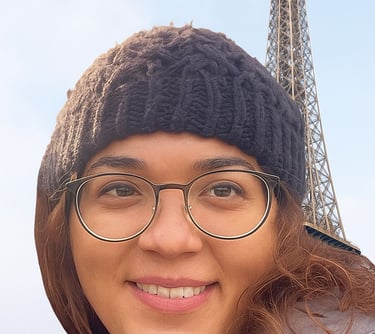 a woman in glasses and a hat on a sunny day