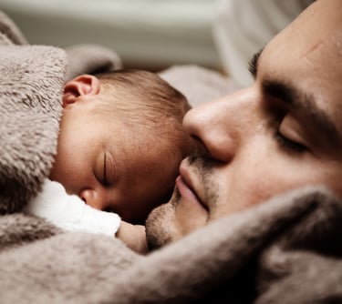 Hombre dormido con su bebé dormido encima de él