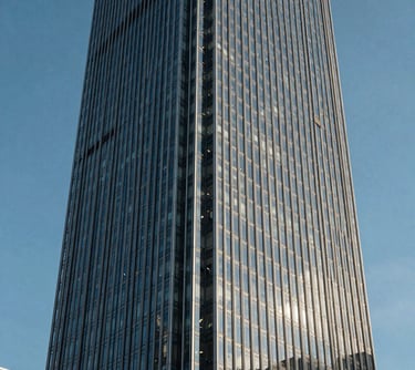 A detailed, architectural photograph of a modern glass skyscraper in a North American financial district, captured with sharp lines and a clear blue sky to represent real estate growth.