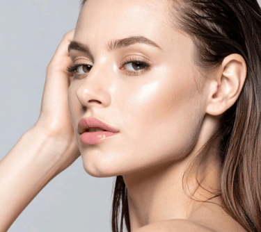 A close-up of a young woman showing off her glowing skin and natural makeup look.
