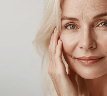 Close-up of a smiling mature woman with blonde hair showcasing healthy aging skin and natural skincare.