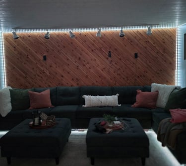 Living room with a large dark gray sectional sofa against a diagonal wood slat accent wall with LED strip lighting.