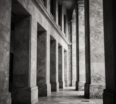 A black and white architectural shot of a corridor in a high court building, showing strong repetitive lines and a sense of order. High contrast with deep navy-like blacks and warm off-white highlights.