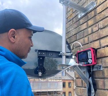 a man in a blue jacket and a red satellite meter installing a sky dish