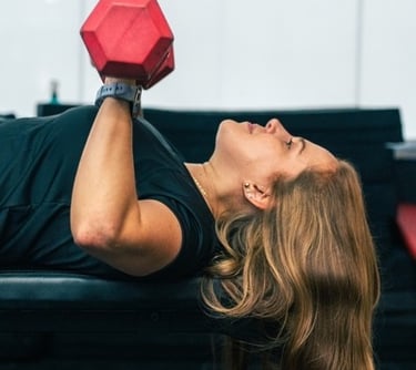 a young lady using dumbbells on a bench