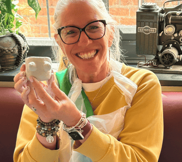 happy hen holding her clay boob pot