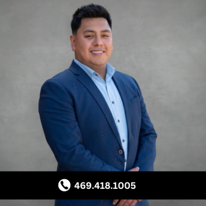 Professional businessman in a navy blue blazer posing for a headshot against a grey background.