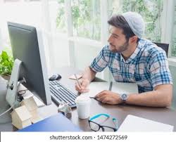 a man sitting at a desk with a laptop and a cup of coffee