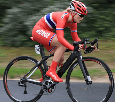Professional female cyclist in red Norway national team kit racing on a carbon fiber road bike.