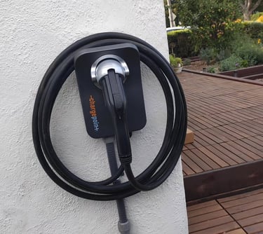 ChargePoint home electric vehicle charging station mounted on a white wall next to a wooden deck.