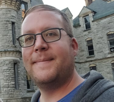 a man in glasses and a blue shirt is taking a selfie