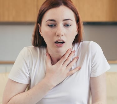 Woman sitting on couch, hands on chest. Get panic attack treatment in Vadodara from best psychiatrist near you