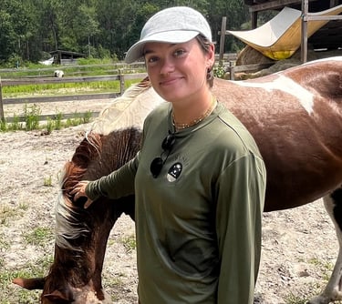 Sierra Sawtelle in a hat and a hat standing next to a horse