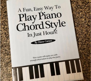 A piano lesson book titled Play Piano Chord Style by Diane Carson sits on a granite countertop.