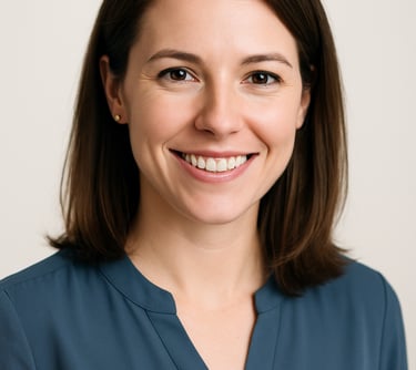 A professional headshot of a female professional with a warm smile, wearing a slate blue blouse. High-key lighting, off white background, modern and clean style. North American / International.