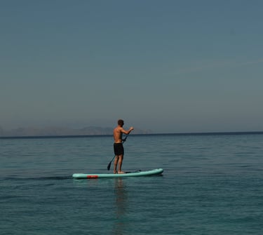 Persona practicando paddle surf en aguas tranquilas frente a la costa de Alcudia