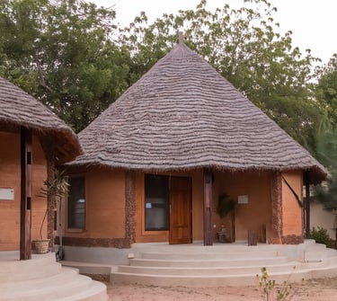 A scenic view of Tendaba Camp, featuring traditional thatched-roof huts and safari tents nestled alo