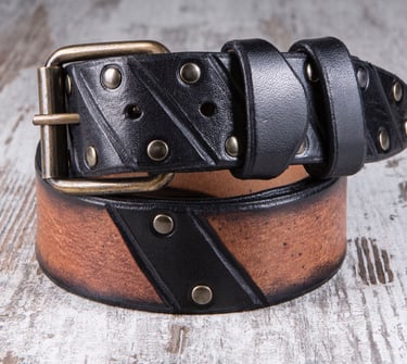 Cintura in cuoio marrone e nero di MaxCuoio con inserti di chiodi arrotolata su un tavolo