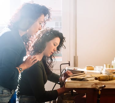 Mujeres aprendiendo técnicas artesanales en taller creativo, trabajando con herramientas manuales en un espacio de joyería.