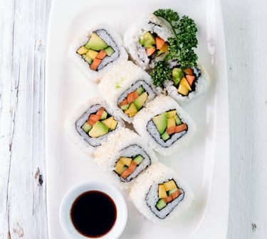 a plate of sushi rolls with sauce and sauce