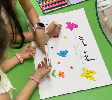 Children decorating an Arabic poster with colorful drawings of butterflies, birds, and flowers