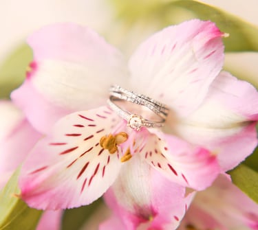 a wedding ring with a diamond ring on top of a flower
