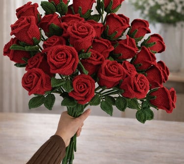 Handmade crochet red rose bouquet with green leaves held in hand indoors