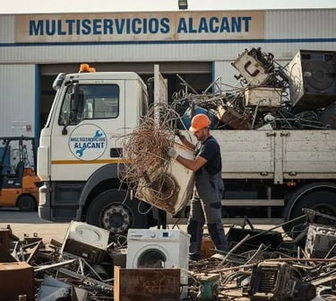 Trabajador recogiendo chatarra delante de la oficina de Multiservicios Alacant, cargando el camión