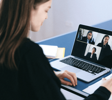 A woman working remotely while attending a video conference call on her laptop.
