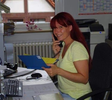 aFrau sitzt an einem Schreibtisch mit einem Telefon in der Hand
