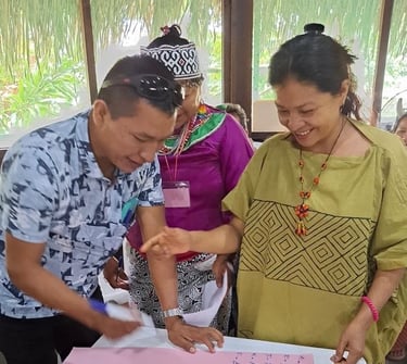 Indigenous community members in traditional attire collaborate on a project during a workshop.