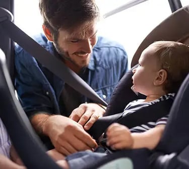 a man and a baby in a car seat