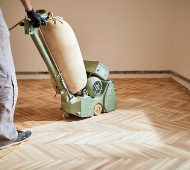 Pro sanding wood floors with a belt sander.