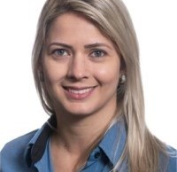 Mulher de cabelos loiros lisos usando camisa jeans azul, fotografada em fundo branco.